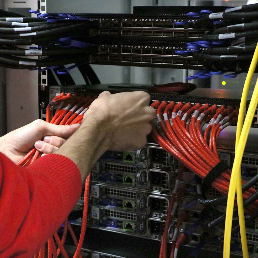 A Physical Infrastructure employee plugging in a very organized array of ethernet cables.