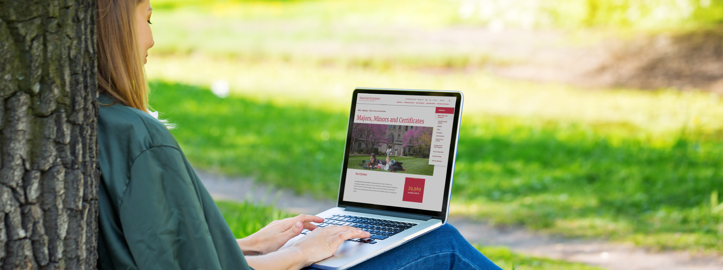 A student browsing the internet on their laptop on campus outside.